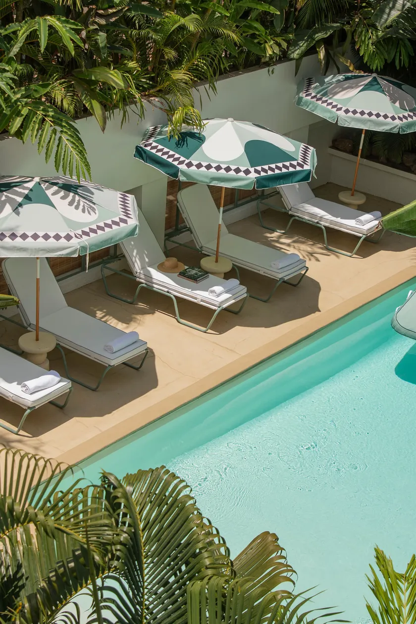 Sun loungers with towels under parasols beside the pool