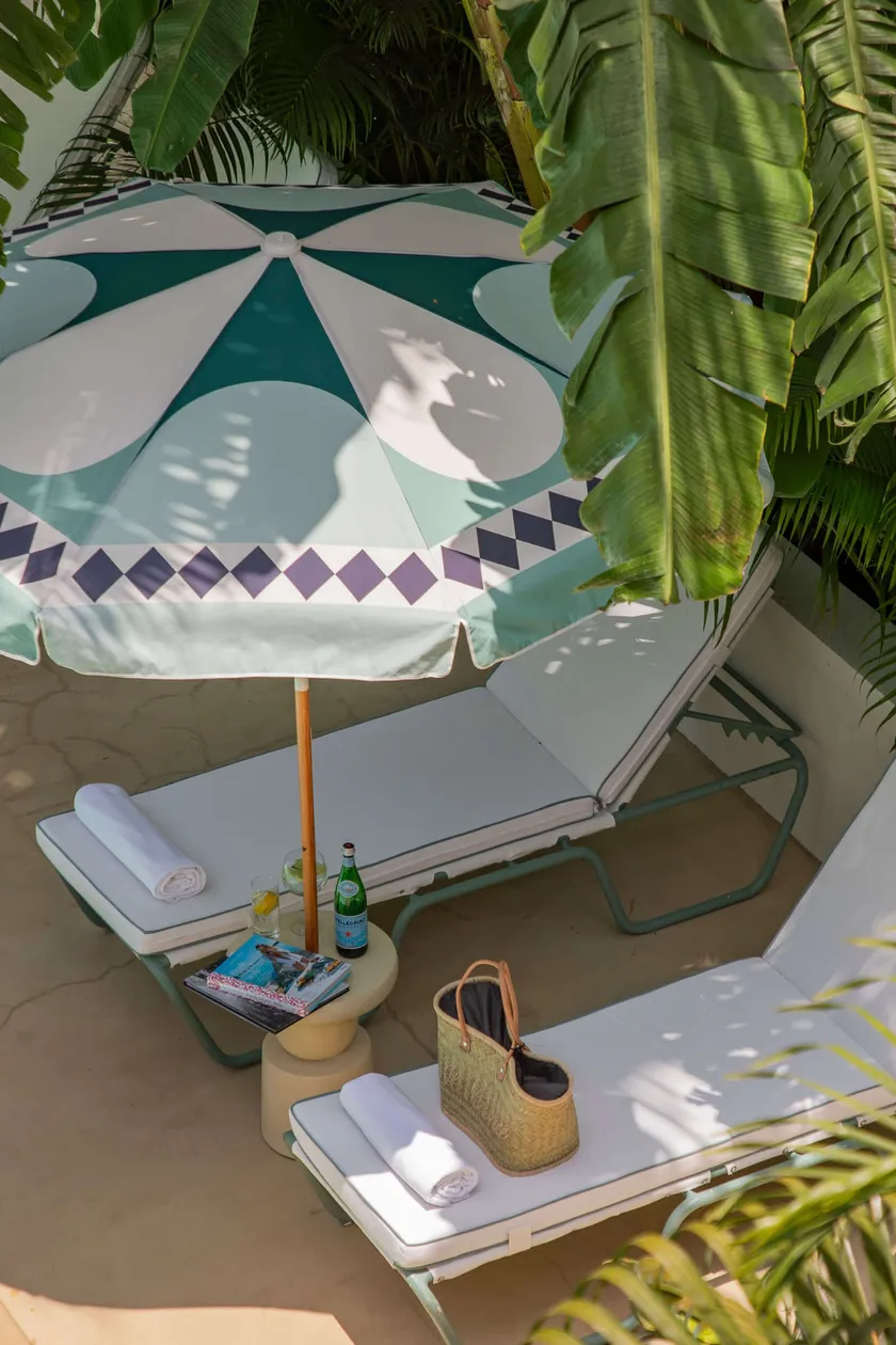 Two sun loungers with towels, a beach bag and a book under a parasol