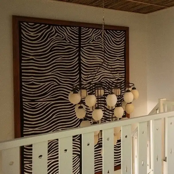 Handmade carpet woven with antique Indian techniques, paired with an ostrich-egg chandelier rescued…