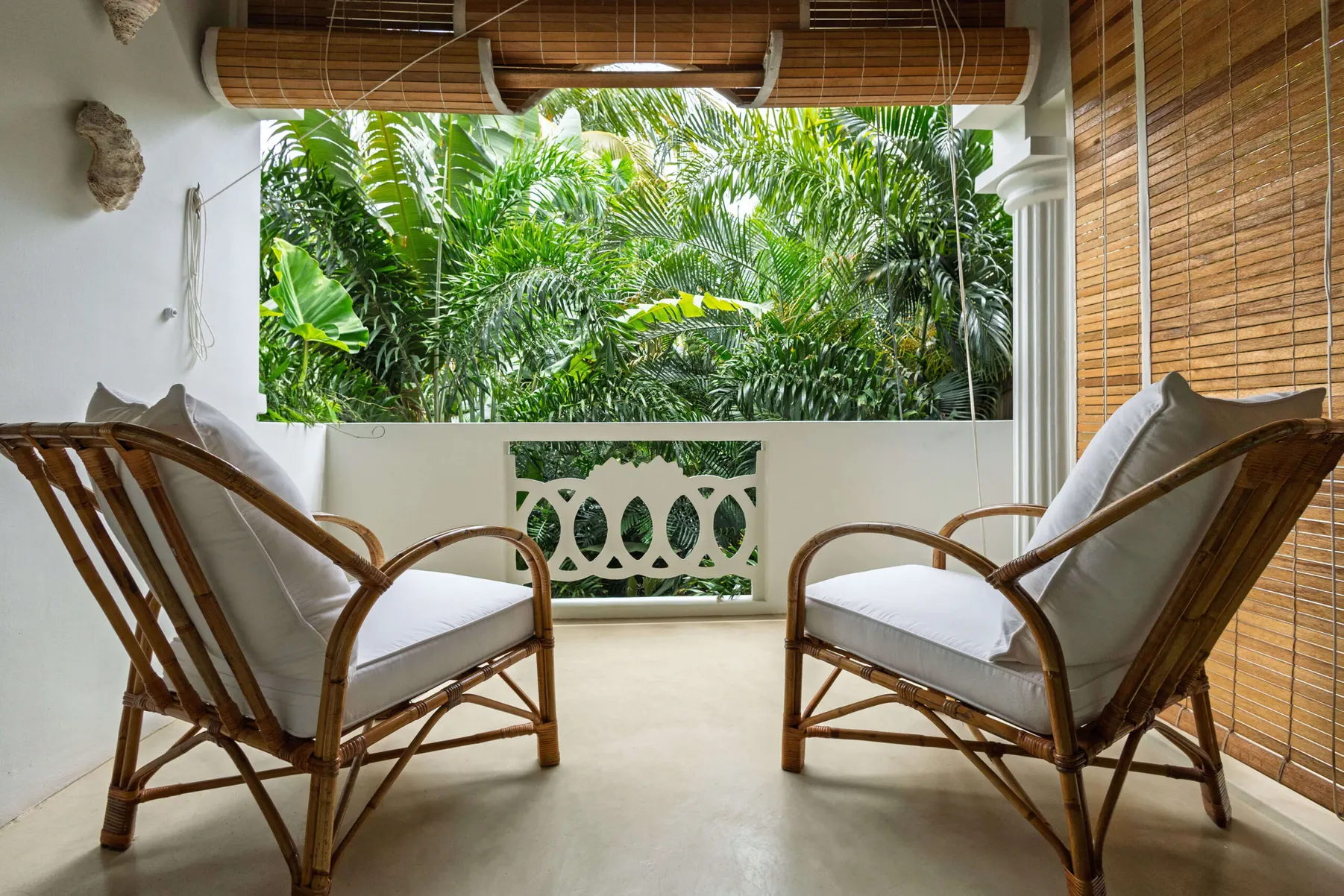 Balcony with two rattan armchairs facing the tropical garden