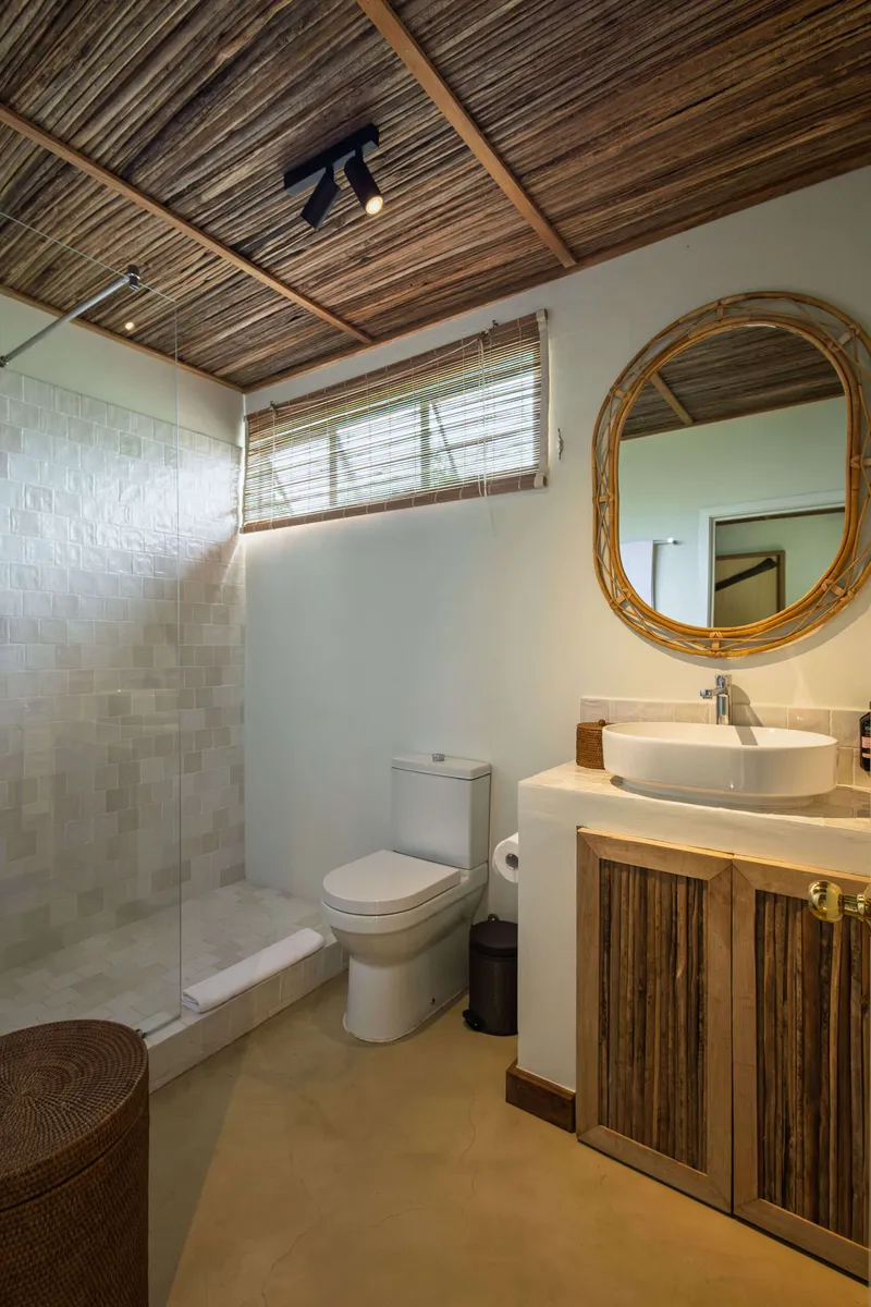 Bathroom with a walk-in shower, washbasin and rattan-framed mirror
