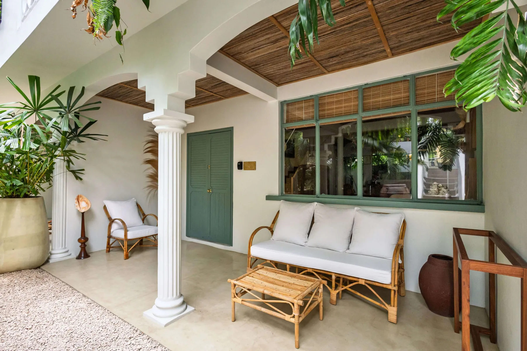 Terrace with a rattan sofa, armchair and coffee table under white arches